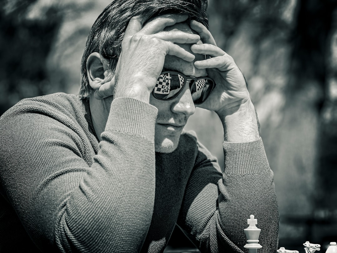 a man sitting at a table with a chess board — Photo by Jay Bhadreshwara on Unsplash