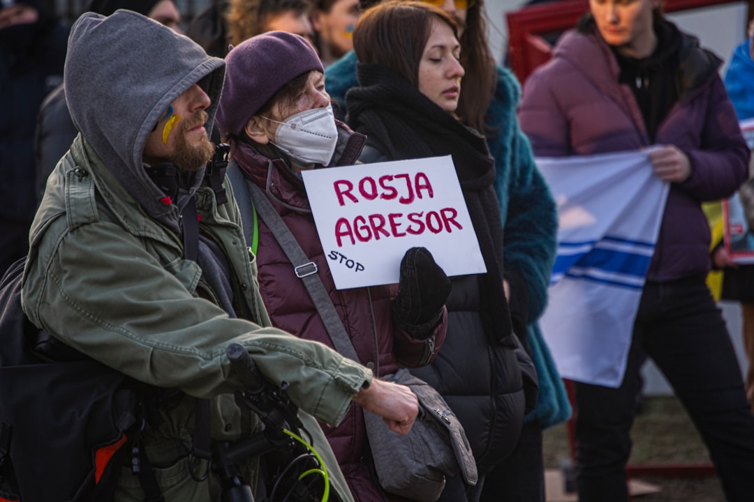 a group of people standing next to each other holding signs — Photo by Stanisław Trajer on Unsplash