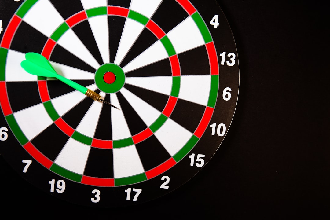 A green dart stuck in a dartboard on black background — Photo by Sasun Bughdaryan on Unsplash