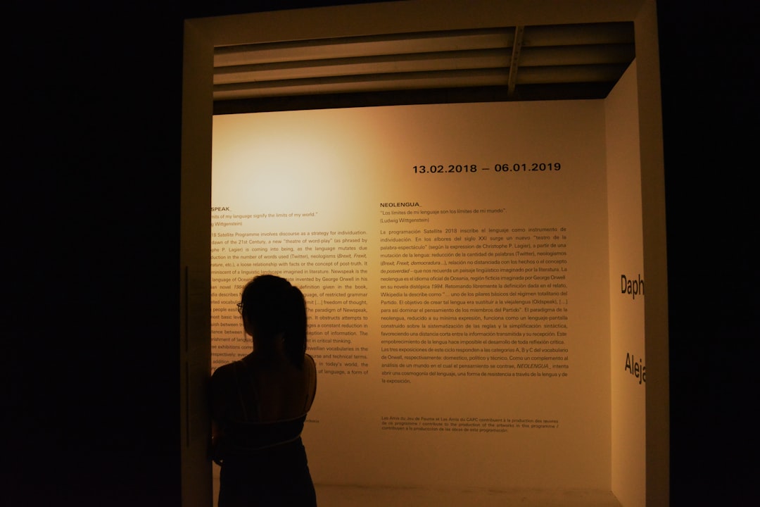 woman leaning beside white printed wall — Photo by Gabrigel on Unsplash