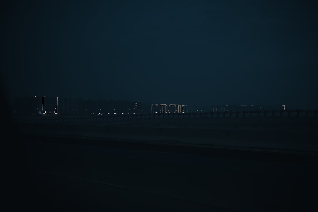 Distant city lights glow against a dark night sky — Photo by Andrey Strizhkov on Unsplash